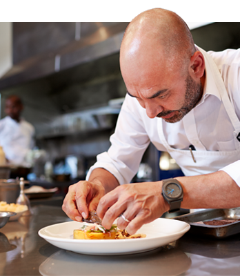 Lifestyle. A chef plating a dish in the kitchen.