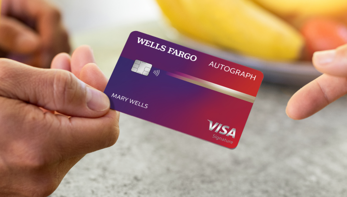 Person's hand holding the Wells Fargo Autograph card and passing it to a second person's hand