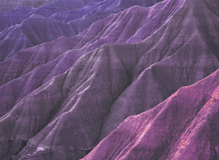 Decorative. Layered purple and pink Badlands hills with eroded ridges and soft shadows.