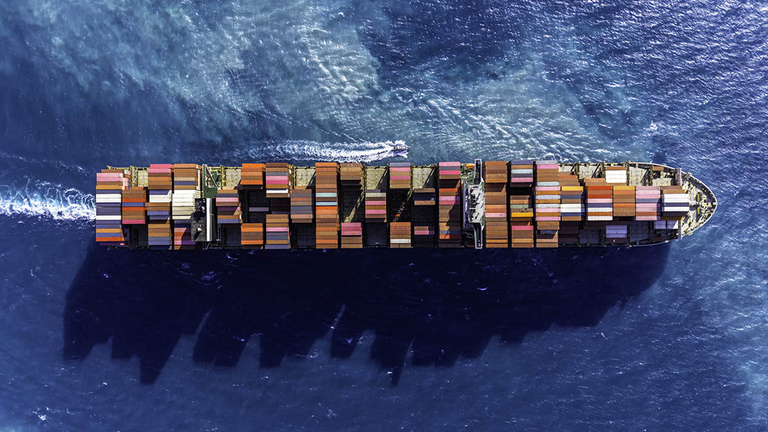 Decorative. Overhead view of loaded container ship moving across water.