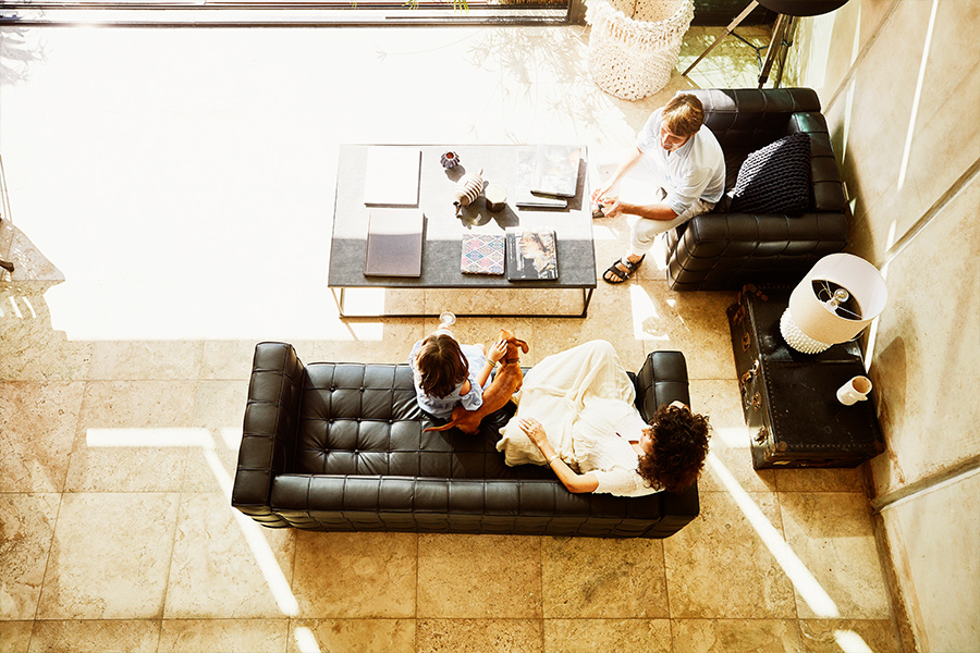 An overhead photo of a family of three discussing their future while sitting on contemporary furniture in the sunlight.